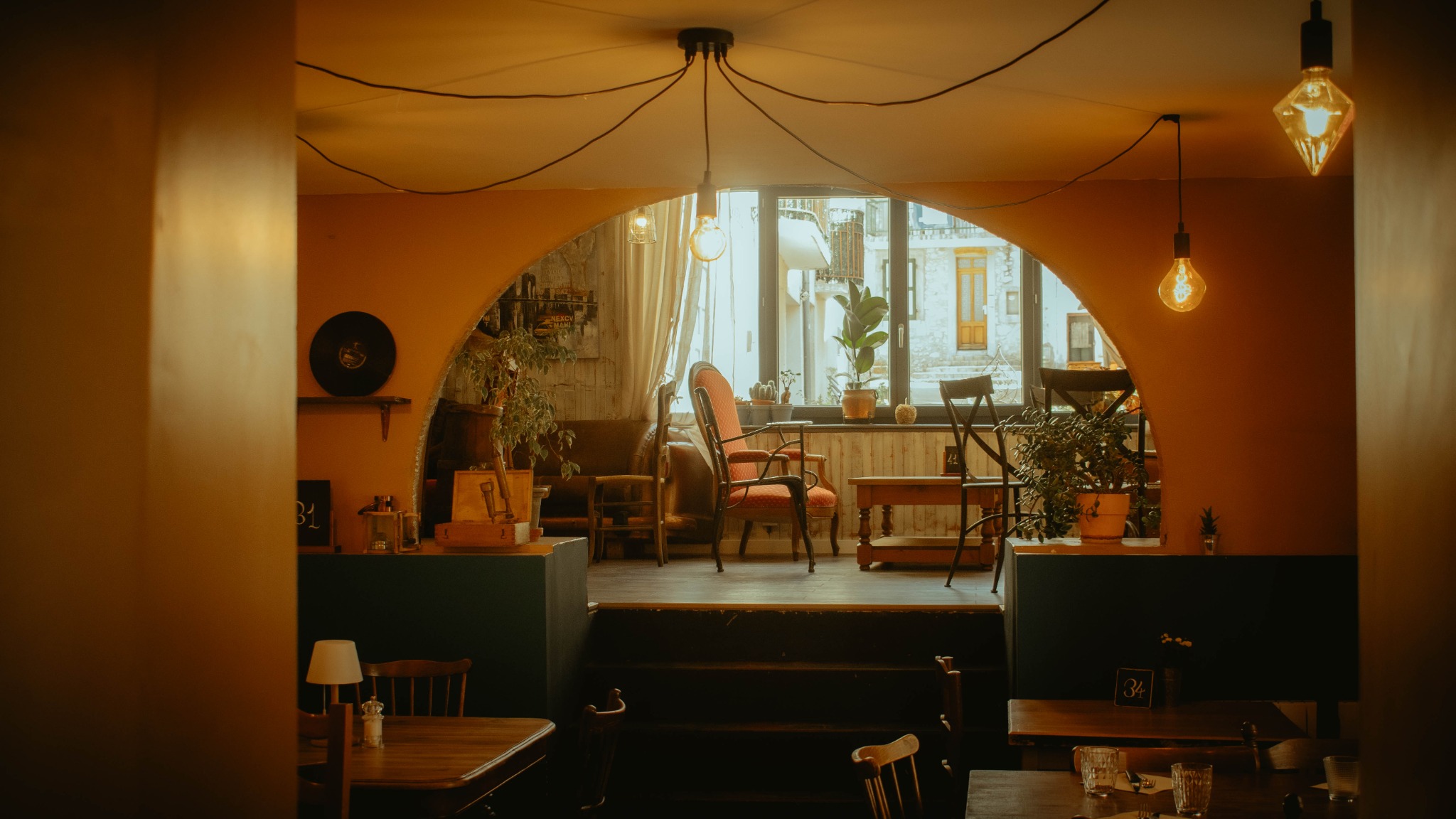Salle de restaurant chaleureuse avec une arche, des plantes et des suspensions